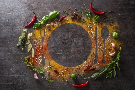 Spices and herbs scattered on the table forming the silhouette of cutlery and a plate. photo