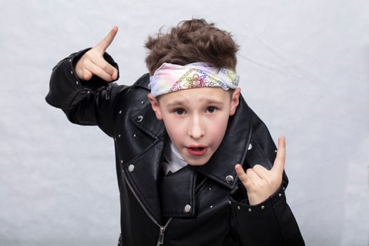 Portrait of a heavy metal boy in sunglasses. Cute teenager in a leather jacket doing a rock and roll sign photo
