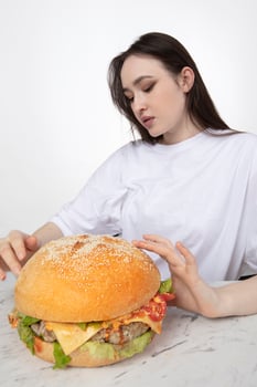 A woman is holding a big barbecue hamburger sandwich on the background. Fast food concept. The girl has a huge hamburger. photo
