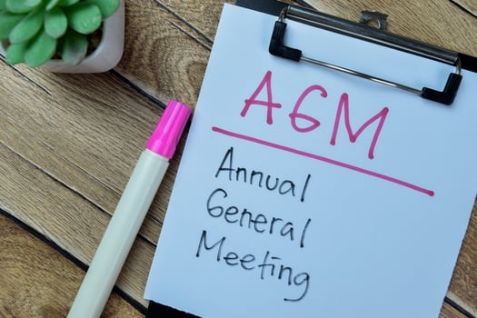 Concept of AGM - Annual General Meeting write on paperwork isolated on Wooden Table. photo