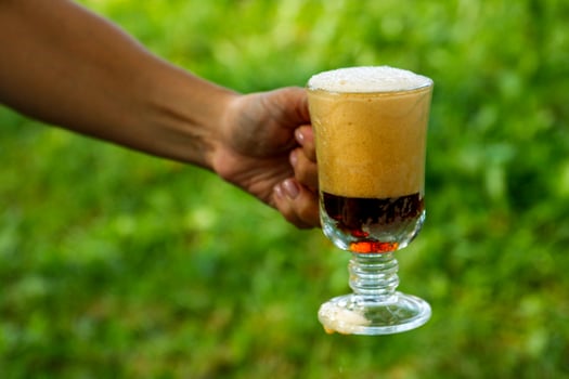 woman's hand holds a full glass of foamy kvass, soft drinks photo