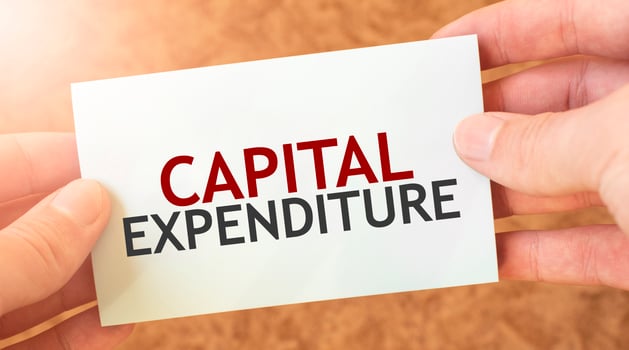 CAPITAL EXPENDITURE word inscription on white card paper sheet in hands of a businessman. recap concept. red and white paper photo