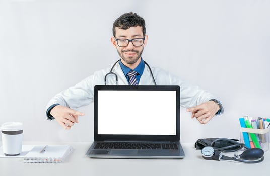 Handsome doctor pointing at an advertisement on the laptop screen. Smiling doctor pointing at an advertisement on the laptop screen photo