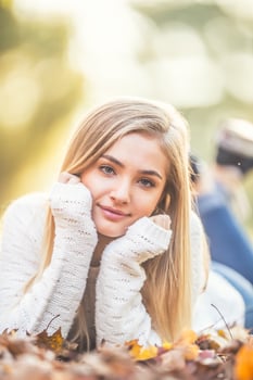 Autumn portrait of young woman lying on maple leaves in park photo
