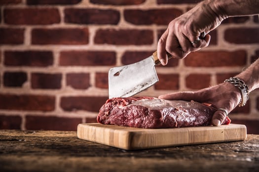 Butcher man hands cutting raw beef steak in butchery photo