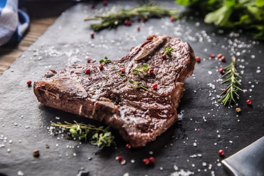 Beef T-Bone steak with salt pepper and rosemary on slate plate photo