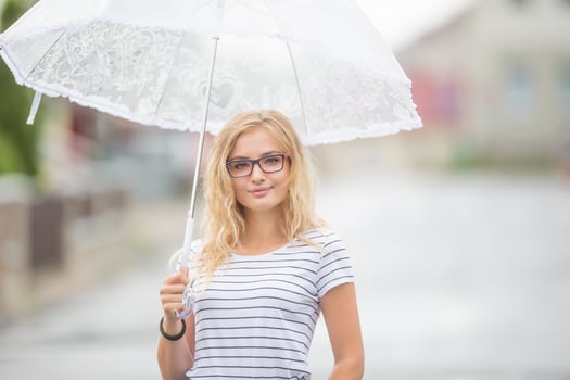 Beautiful young blonde girl holding umbrella in summer rain photo