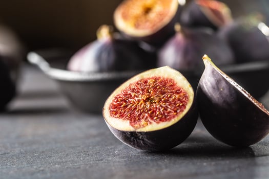 A few figs in a black bowl on an dark concrete table photo