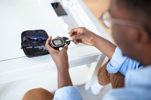 Young african man using digital glucometer at home. Diabetes control photo