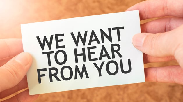 WE WANT TO HEAR FROM YOU word inscription on white card paper sheet in hands of a businessman. recap concept. red and white paper photo