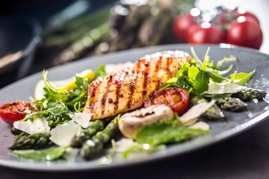 Grilled chicken breast asparagus arugula mushrooms tomatoes lemon and parmesan cheese. photo