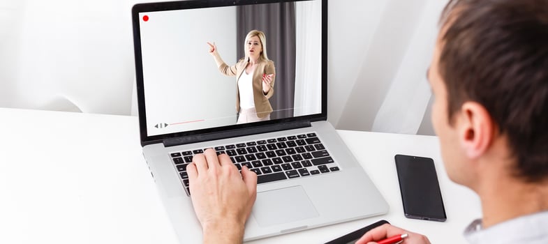 Online video tutorial concept. male using laptop or pc on wooden table photo