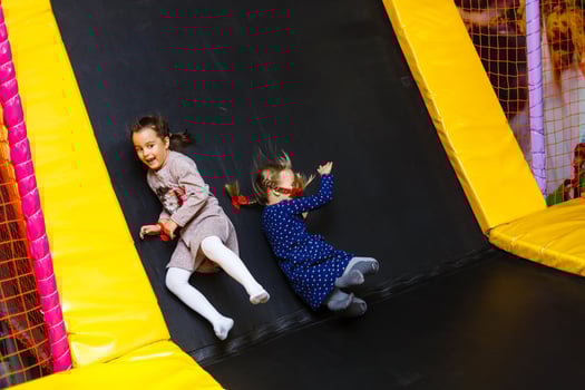 Child jumping on colorful playground trampoline. Kids jump in inflatable bounce castle on kindergarten birthday party Activity and play center for young child. Little girl playing outdoors in summer. photo