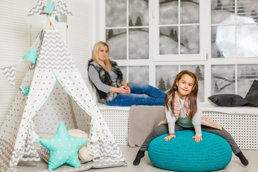 A young mother in a gray sweater and daughter are sitting in the children's room in winter. the Christmas and New Year's interior. Holiday. Family concept. photo