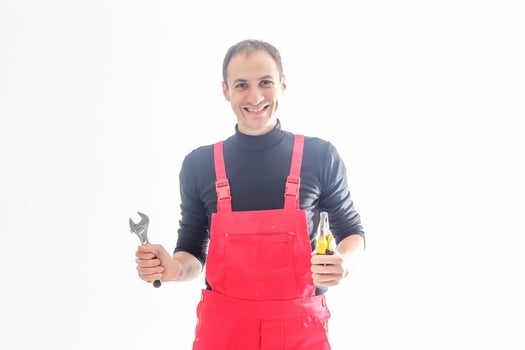 Young mechanic in uniform with crossed arms and wrenches standing, isolated on white photo