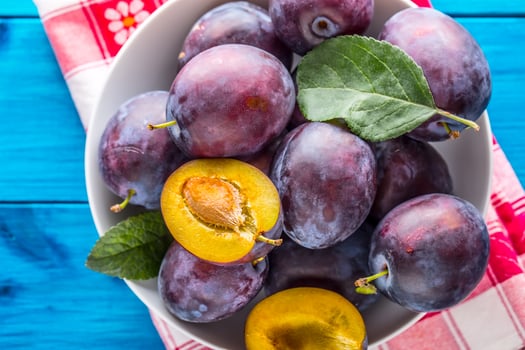 Plums. Fresh juicy plums in a bowl on a wooden or concrete board photo