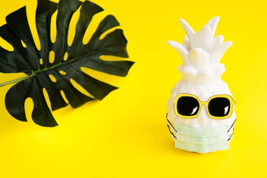 Pineapple in a medical mask and sunglasses on yellow background. Summer in Covid-19. Vision for the summer of 2020 during the coronavirus pandemic. photo
