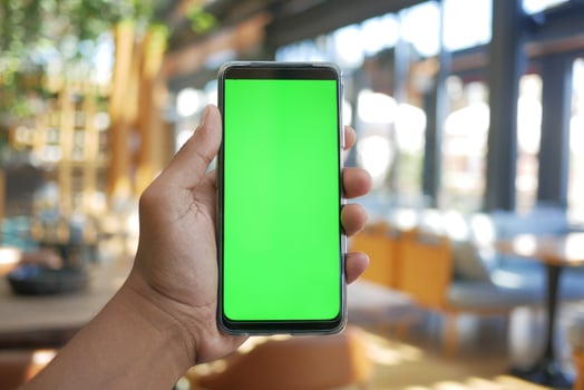 young man hand using smart phone with green screen at cafe photo
