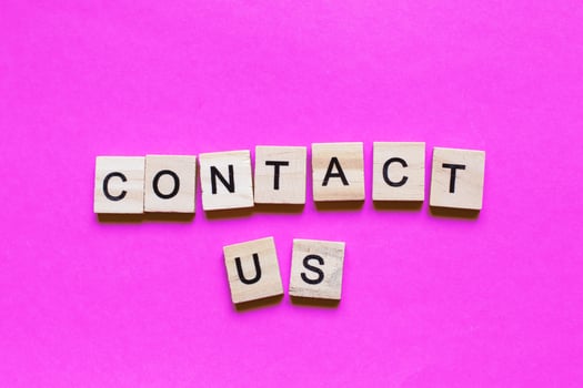 Word contact us made from wooden cubes on a pink paper background. photo