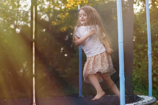 Little child girl jumping on the trampoline in the back yard photo