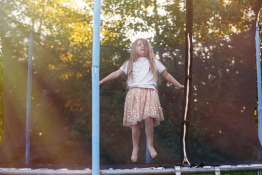 Little child girl jumping on the trampoline in the back yard photo