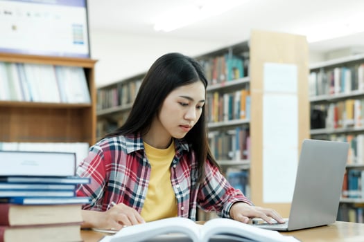 Young university student using laptop for online learning, searching and learning at library. photo