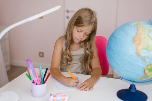 Girl sits at home at a table and write in a notebook, completing a learning task or repeating lessons at home photo