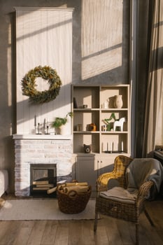 Scandinavian interior of a country house. A living room with a fireplace and a wicker armchair with a plaid by the window, decorated for Christmas. Shelves with vases and candles photo