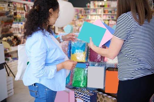 Rear view of a saleswoman and customer in creative art store. Pregnant woman shopping for school stationery photo