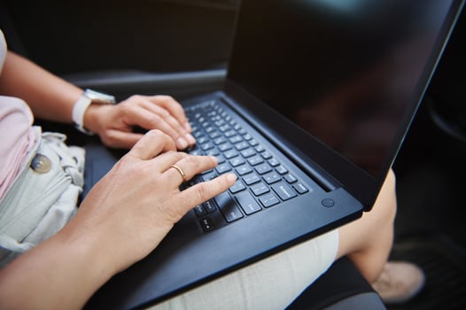 Close-up image of business woman hands typing a text message on laptop while sitting in driver seat in the car photo
