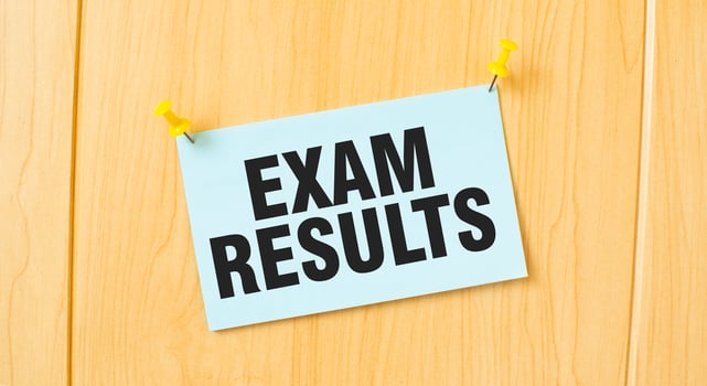 EXAM RESULTS sign written on sticky note pinned on wooden wall photo