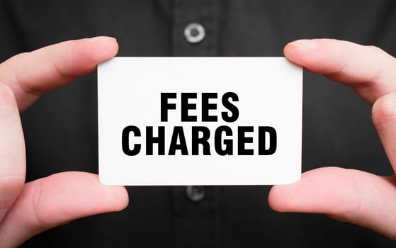 Businessman holding a card with text FEES CHARGED, business concept photo