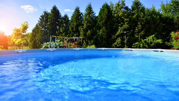 Swimming pool with metal frame for home and garden. Frame swimming pool in the yard. Garden in the background. Summer holiday fun and recreation. photo