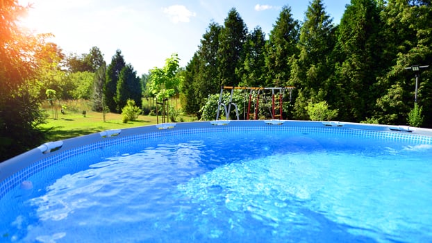 Swimming pool with metal frame for home and garden. Frame swimming pool in the yard. Garden in the background. Summer holiday fun and recreation. photo