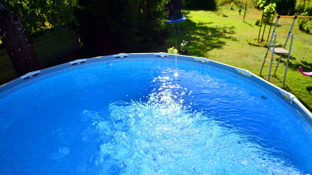 Swimming pool with metal frame for home and garden. Frame swimming pool in the yard. Garden in the background. Summer holiday fun and recreation. photo