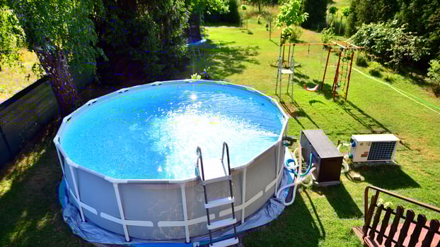 Swimming pool with metal frame for home and garden. Frame swimming pool in the yard. Garden in the background. Summer holiday fun and recreation. photo