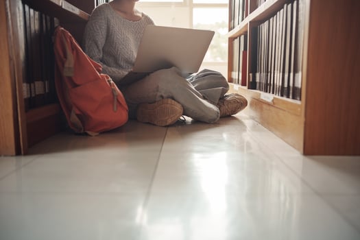 Student girl sitting on floor and using laptop, Writes notes for paper, Essay, Study for class assignment. Diverse group of Students Learning, Studying for Exams. photo
