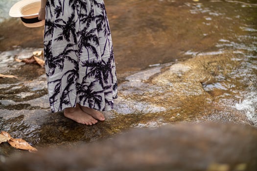 young women tourist in vintage dress stands alone on rock by waterfall in the forest hoping to cool down for swim. The back of young Asian women tourist who enjoys playing in waterfall alone. photo
