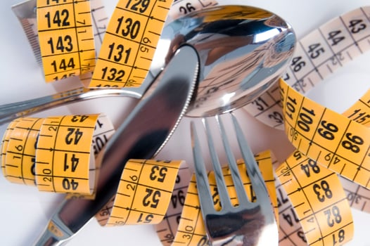 a fork and knife surrounded by measuring tape photo