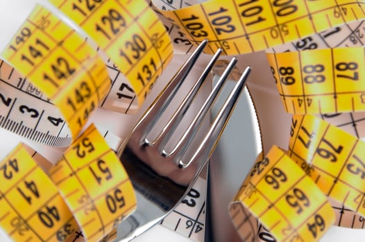 a fork and knife surrounded by measuring tape photo