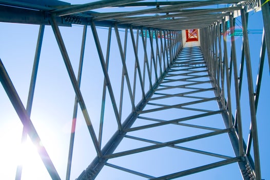 the sun shines through the metal structure of an oil rig photo