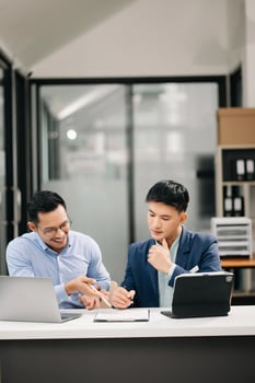 Two Asian business workers talking on the smartphone, tablet and using laptop at the office. photo