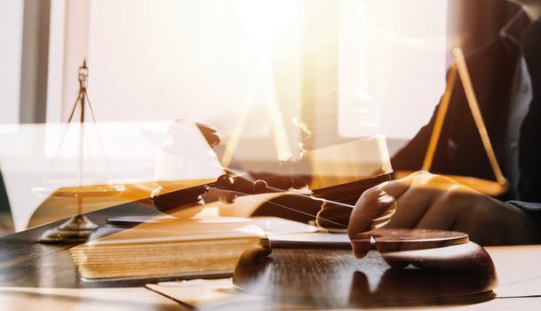 Justice and law concept.Male judge in a courtroom with the gavel, working with, computer and docking keyboard, eyeglasses, on table in morning light photo