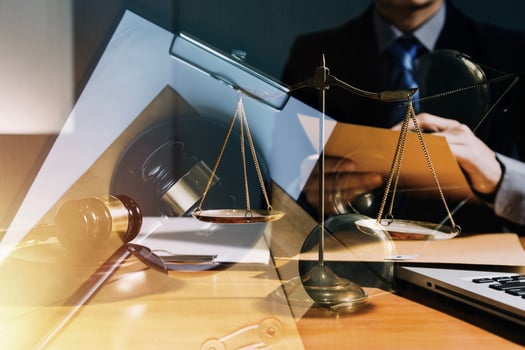 Justice and law concept.Male judge in a courtroom with the gavel, working with, computer and docking keyboard, eyeglasses, on table in morning light photo