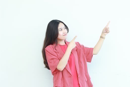 portrait of beautiful asian woman wearing red outfit pointing to the side for copy space photo