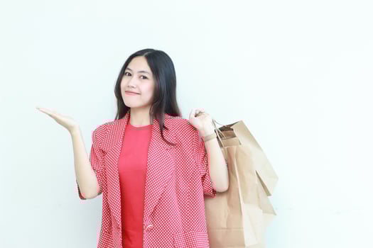 portrait of beautiful asian woman wearing red outfit gesturing carrying lots of shopping bags with happy expression photo
