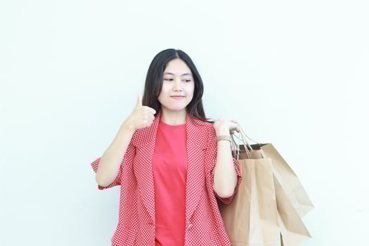 portrait of beautiful asian woman wearing red outfit gesturing carrying lots of shopping bags with happy expression photo