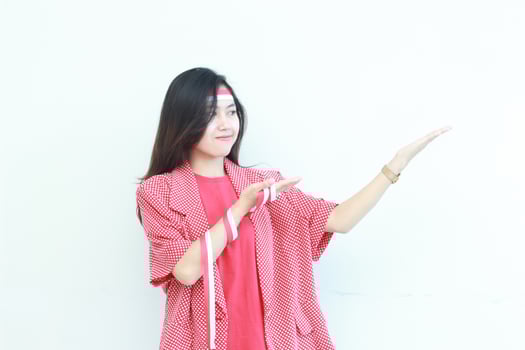 portrait of beautiful asian woman wearing red outfit celebrating Indonesia independence day pointing to the side for copy space photo