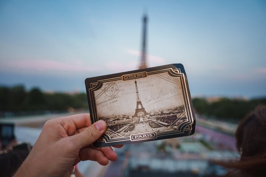 Person holding a photo of the Eiffel Tower in Paris