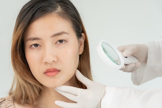 skin problem and beauty of asian girl. Dermatologist use magnifying glass look itchy skin from skin allergic, steroid allergy, sensitive skin, chemical allergy, rash, insect bites, Dermatitis. photo
